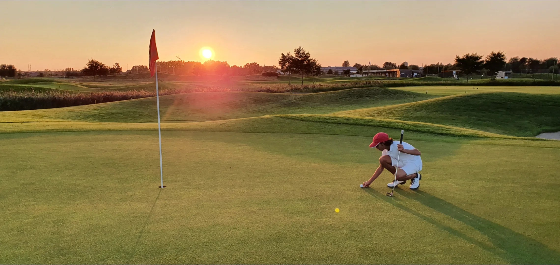 A golfer reading the green at sunset in KADI apparel