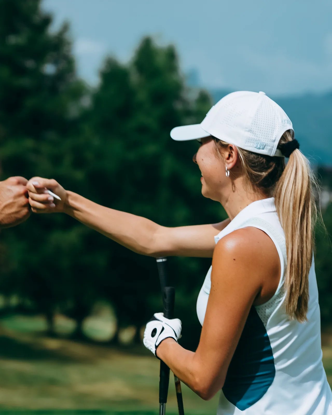 Two golfers in KADI caps sharing a fist bump between holes on the course